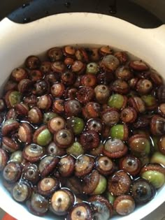 a bowl filled with lots of brown and green beads next to a black stove top