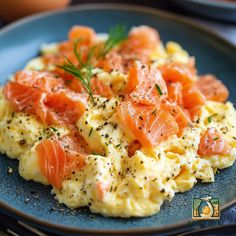 a blue plate topped with scrambled eggs covered in salmon and dill sprinkles