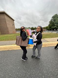 two women are standing in the street and one is holding a bag