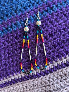 two pairs of colorful beaded earrings sitting on top of a crocheted blanket