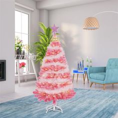 a pink christmas tree in the middle of a living room with blue chairs and a fireplace