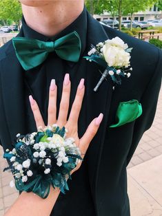 a man in a tuxedo with flowers on his wrist and two boutonnieres