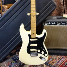 an electric guitar sitting on top of a rug next to a suitcase and amps