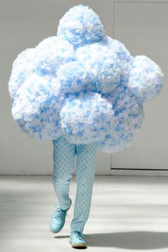 a woman is walking down the runway with a large cloud on her head and legs