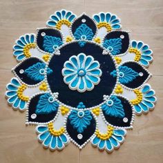 a blue and yellow flower design is on the floor with white, yellow, and black beads