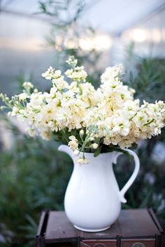 a white vase filled with flowers sitting on top of a wooden box