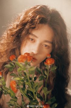 a woman with long hair holding flowers in her hand