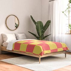 a bedroom with a bed, mirror and plant in it