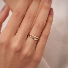 a woman's hand with a gold ring and two diamond rings on her fingers