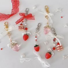 several charms are displayed on a white surface with red ribbons and laces around them