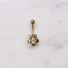 a gold flower belly ring on a marble surface