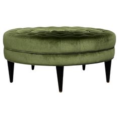 a green ottoman with wooden legs and an upholstered cushion on the back side