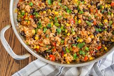 a large pot filled with rice, beans and veggies on top of a wooden table