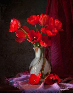 a vase filled with red flowers on top of a table