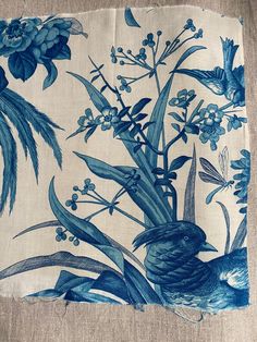 a blue bird sitting on top of a piece of cloth next to flowers and leaves