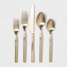 gold flatware is laid out on a white surface