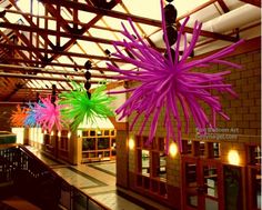 three colorful paper flowers hanging from the ceiling