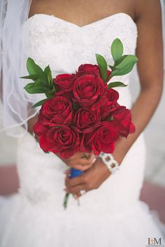 a bride holding a bouquet of red roses