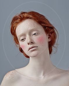 a red headed woman with freckles on her face and chest is looking at the camera