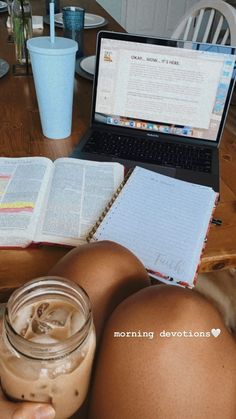 a person sitting at a table with a book and laptop on their lap next to a drink