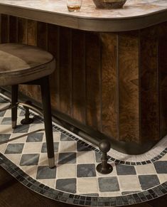 an old fashioned bar with two stools and a bowl of fruit on the counter