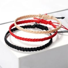 three braided bracelets sitting on top of a white box