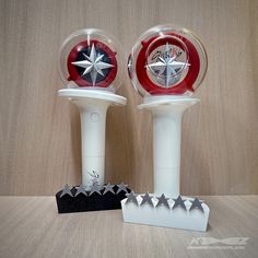 two red and white clocks sitting next to each other on top of a wooden table