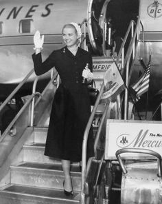 an old photo of a woman standing on the steps of an airplane with her hand up