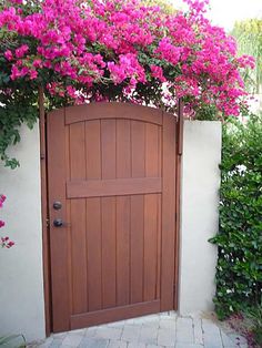 a wooden door with pink flowers growing over it