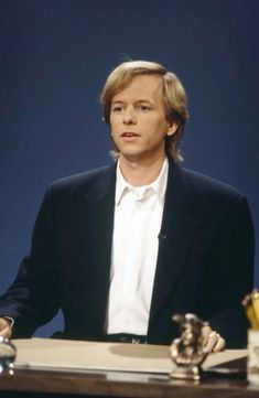 a man sitting at a table in front of a desk with a cup and saucer on it