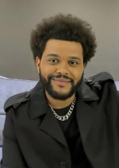 a man wearing a black jacket sitting on top of a couch