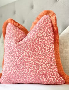 two pink and orange pillows sitting on top of a couch