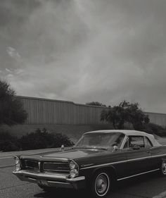 an old black and white photo of a car parked on the side of the road