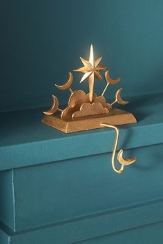 a golden clock sitting on top of a blue shelf next to a candle holder with stars and crescents