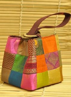 a multicolored patchwork purse sitting on top of a bamboo mat with a brown strap