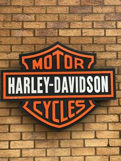 a sign on the side of a brick building that says harley davidson cycles in black and orange