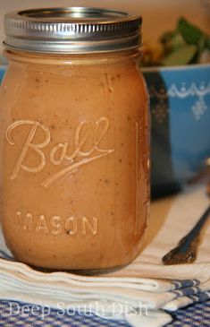 a mason jar sitting on top of a table next to a bowl of fruit and a spoon