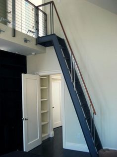 an empty room with a stair case and open closets on the wall next to it