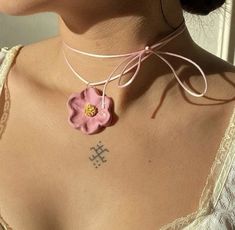 a woman wearing a pink necklace with a flower on the back of her neck,