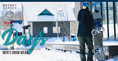 a man holding a snowboard standing next to a building in the snow with his hands on his hips