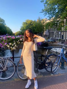 a woman in a white dress standing next to some bicycles