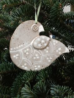 an ornament hanging from a christmas tree in the shape of a bird with pearls