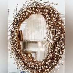 a wreath is hanging on the front door with white flowers and pearls around it,