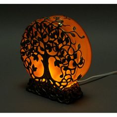 an orange lamp that has a tree on it and is lit up in the dark