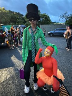 a man in a top hat and green jacket standing next to a clown on a skateboard