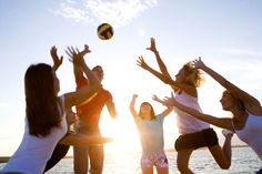 four girls are playing with a volleyball ball on the beach at sunset or sunrise time