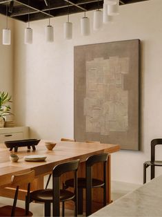 a dining room table with four chairs and a large painting on the wall behind it