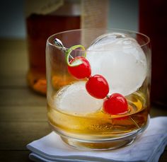 a glass filled with ice and cherries on top of a table