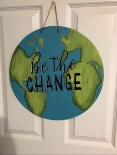 a sign that says be the change hanging on a door with an earth globe painted on it