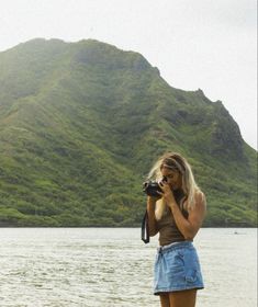 a woman is standing on the beach with a camera